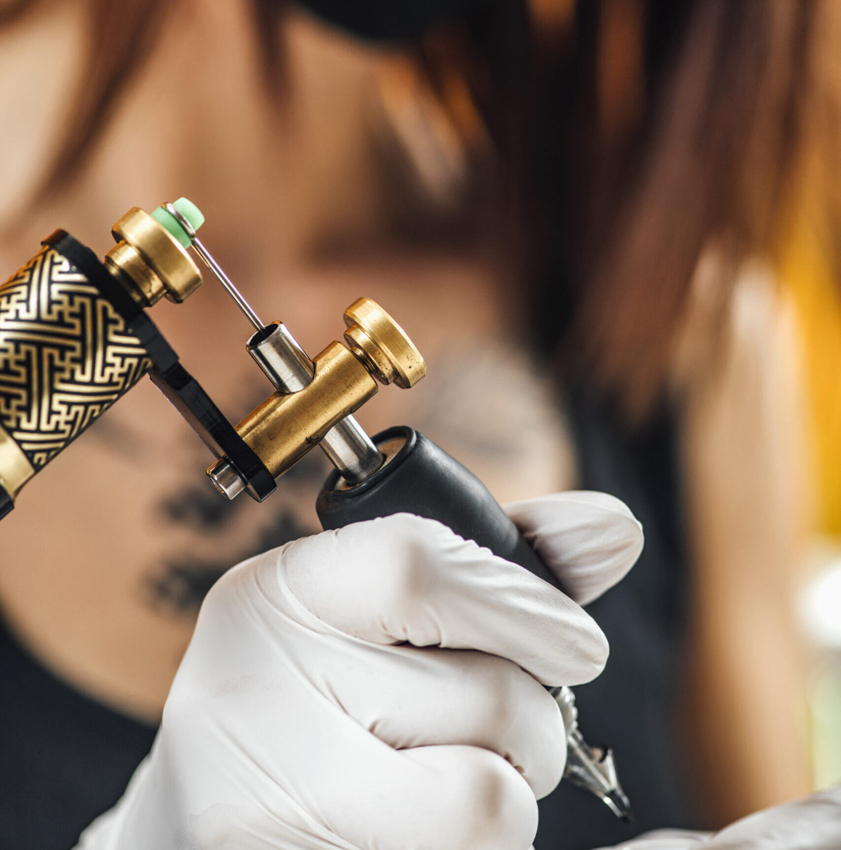 Vrouwelijke tatoeëerder bereidt tatoeagemachine voor om een ​​tatoeage op de arm van een man te maken